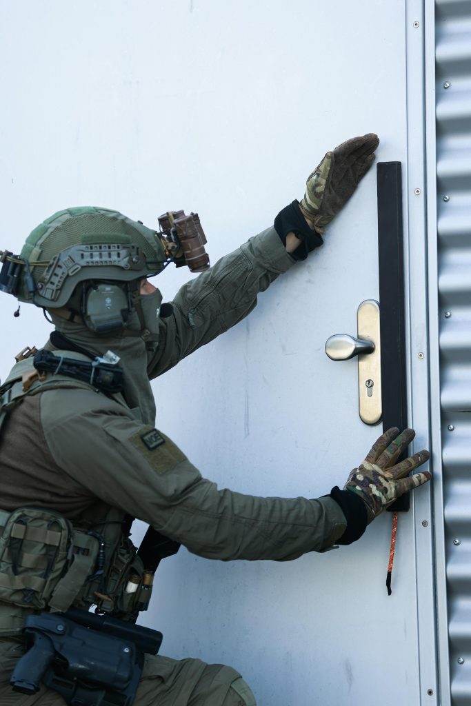 Polizeibeamter bringt eine Türsprengladung kontrolliert an einer Stahltür an.